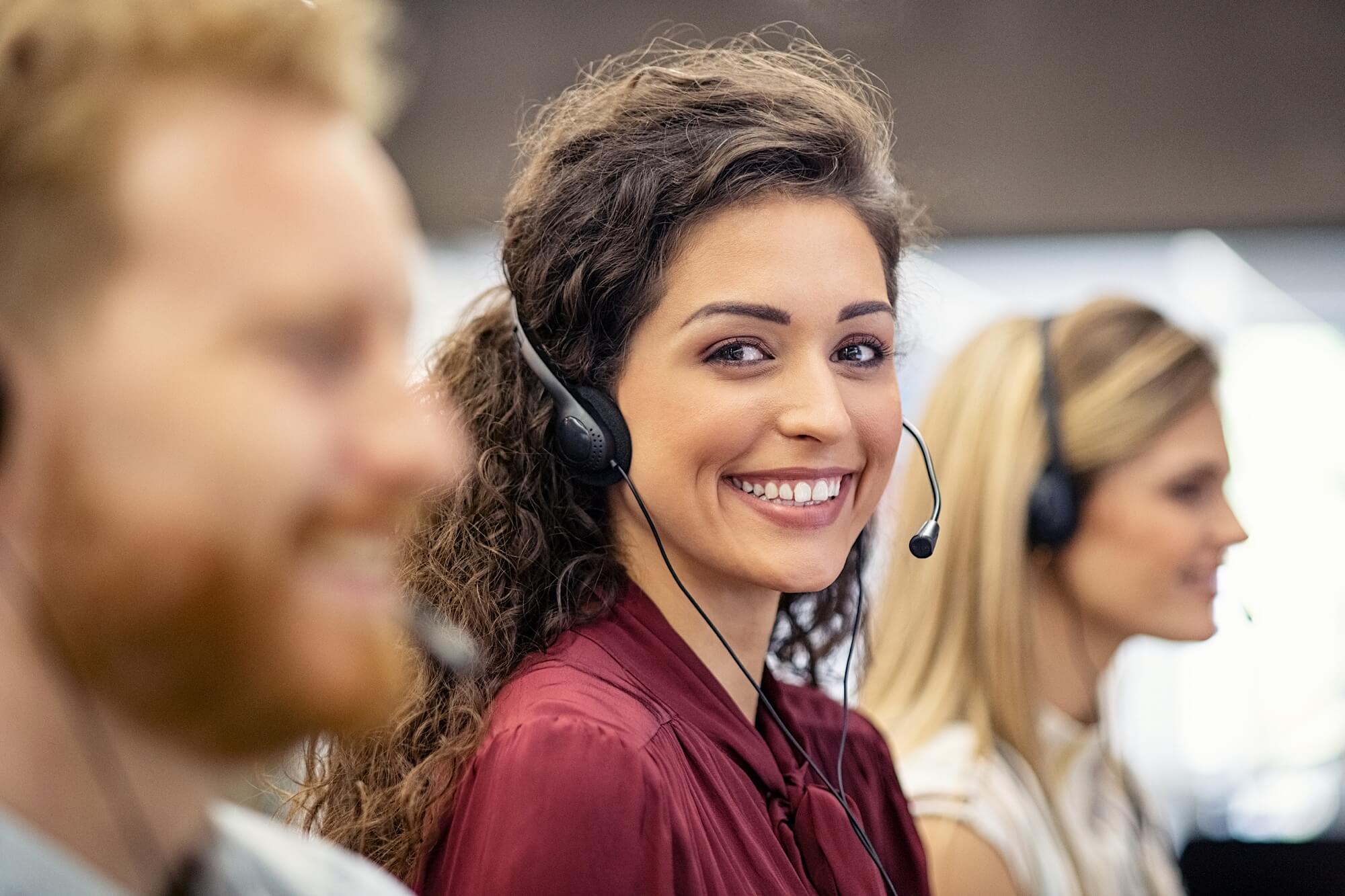 A smiling woman wearing a headset and working in call center
