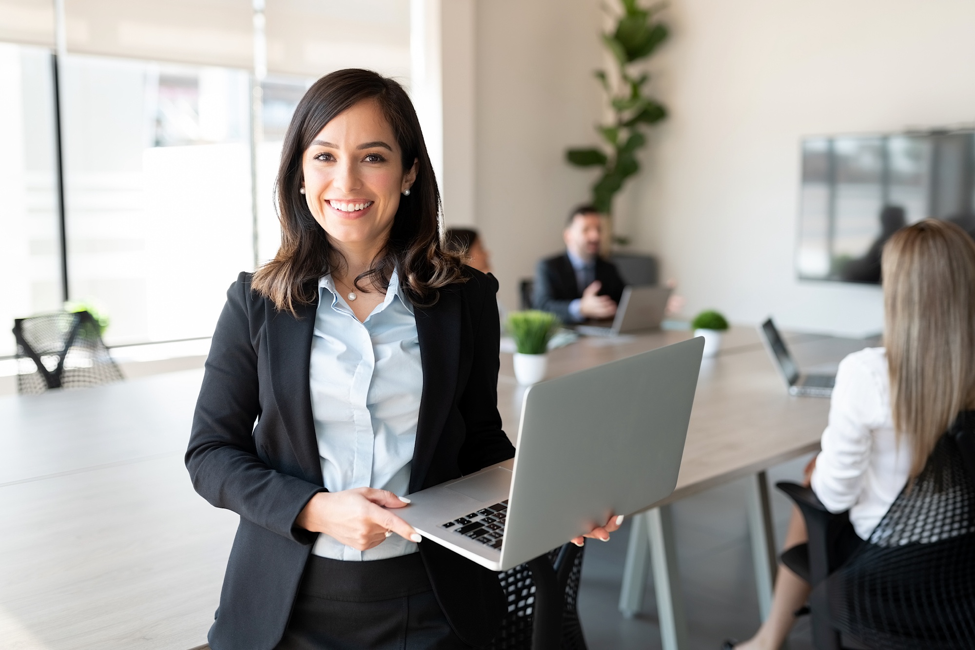 Smiling female entrepreneur with laptop in a meeting room